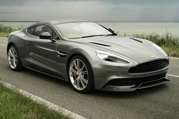 Серебристый суперкар aston martin am 310 на дороге на фоне неба